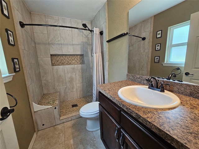 bathroom with vanity, a tile shower, toilet, and tile patterned floors