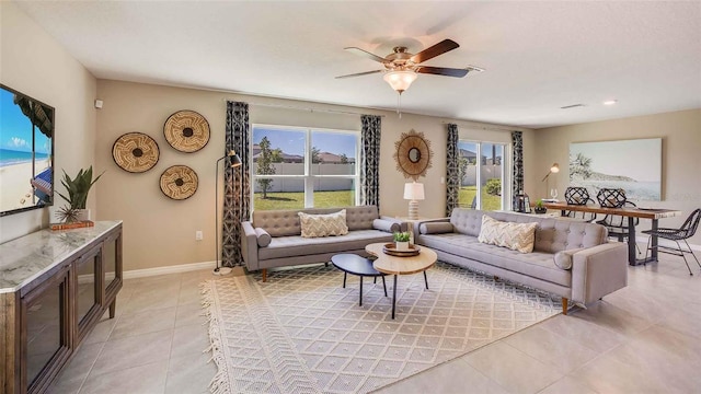 living room with light tile patterned floors, ceiling fan, and baseboards