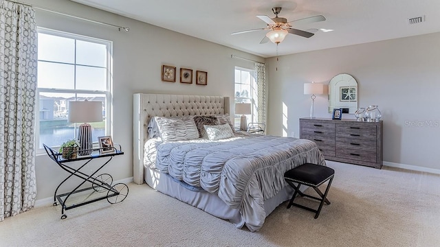 carpeted bedroom featuring a ceiling fan, visible vents, and baseboards