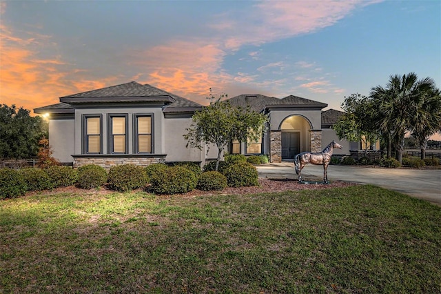 view of front of property with stone siding, driveway, and stucco siding