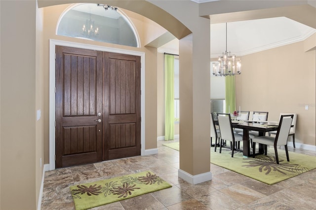 entryway with a chandelier, baseboards, and crown molding