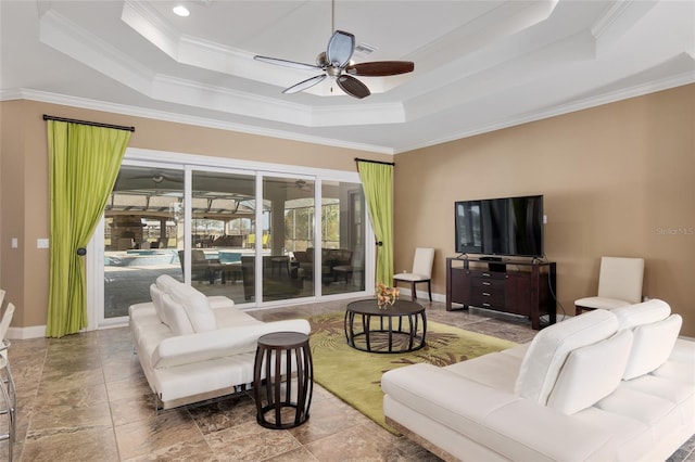 living room featuring crown molding, baseboards, a raised ceiling, and a ceiling fan