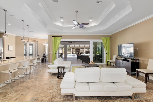 living room with plenty of natural light, visible vents, a tray ceiling, and french doors