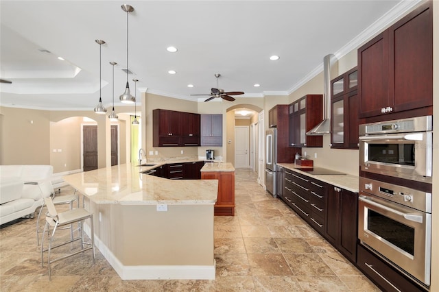 kitchen featuring arched walkways, a kitchen island, appliances with stainless steel finishes, a breakfast bar area, and a sink