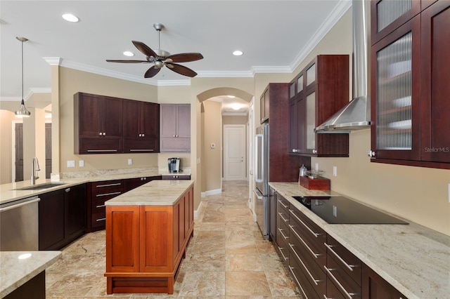 kitchen featuring arched walkways, decorative light fixtures, stainless steel appliances, a sink, and wall chimney exhaust hood