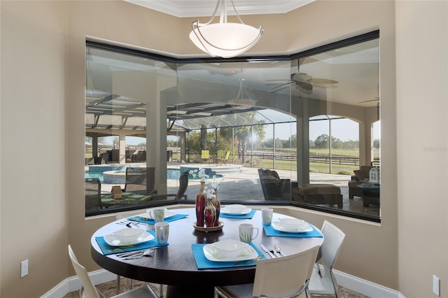 dining area with crown molding, a sunroom, ceiling fan, and baseboards