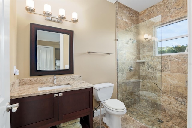 full bath featuring toilet, tiled shower, and vanity