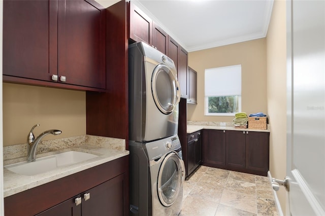 clothes washing area with ornamental molding, a sink, cabinet space, and stacked washer / drying machine