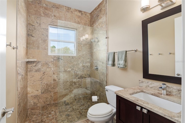 full bath with vanity, a tile shower, and toilet