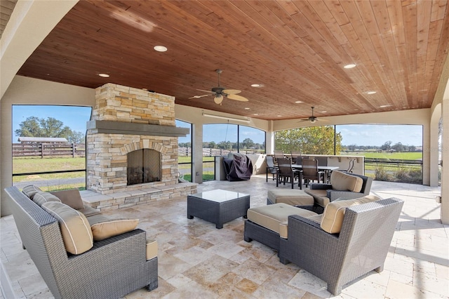 view of patio / terrace with an outdoor living space with a fireplace, outdoor dining space, fence, and a ceiling fan