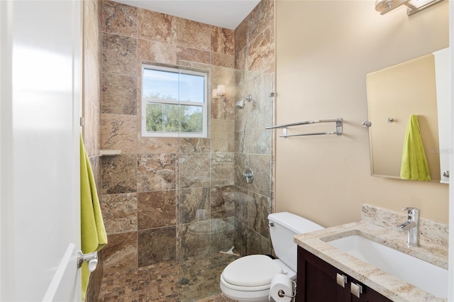 bathroom featuring tiled shower, vanity, and toilet