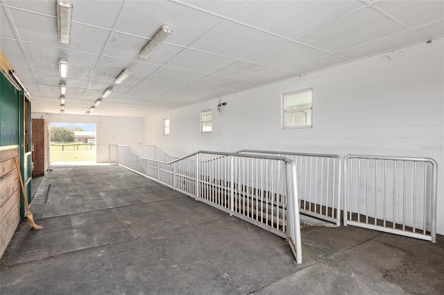 interior space with concrete block wall, concrete floors, and a drop ceiling