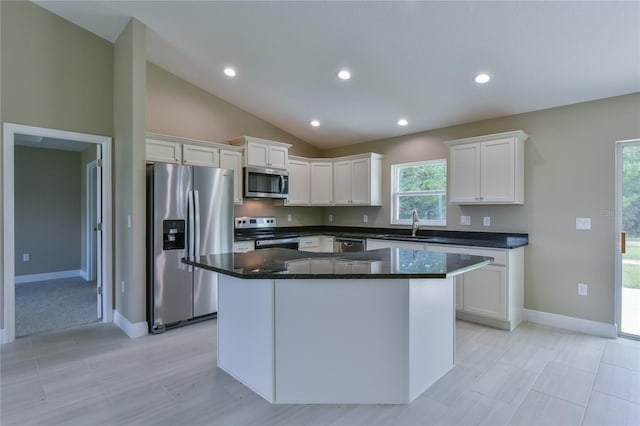 kitchen with a kitchen island, vaulted ceiling, stainless steel appliances, white cabinetry, and a sink