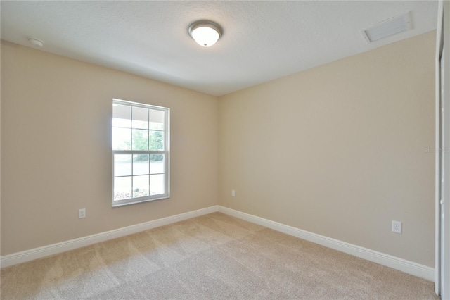 spare room featuring visible vents, light carpet, and baseboards