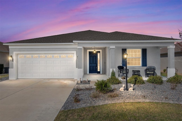 single story home with an attached garage, driveway, a porch, and stucco siding