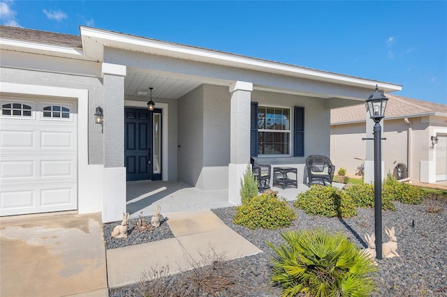 doorway to property featuring covered porch, a garage, and stucco siding