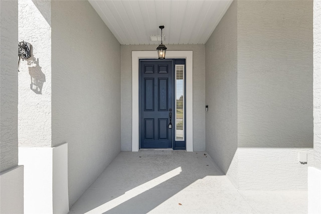 entrance to property with visible vents and stucco siding