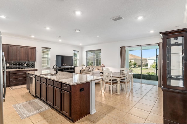 kitchen with dark brown cabinetry, tasteful backsplash, visible vents, a sink, and stainless steel dishwasher