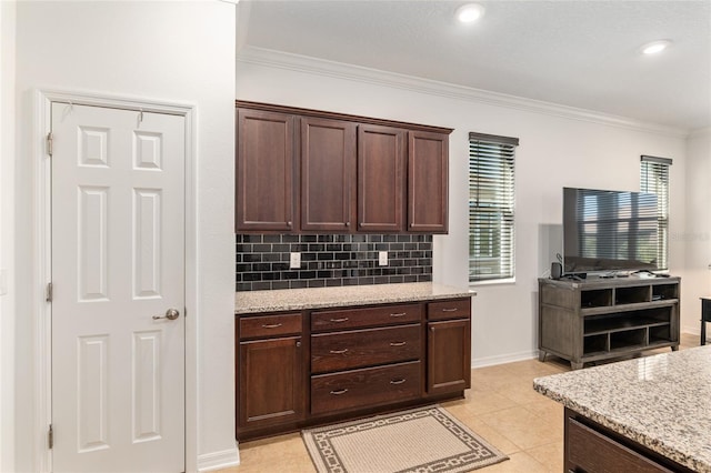 kitchen featuring tasteful backsplash, dark brown cabinets, ornamental molding, and light stone countertops