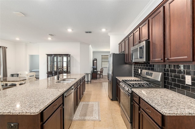 kitchen featuring light tile patterned floors, a sink, visible vents, appliances with stainless steel finishes, and an island with sink