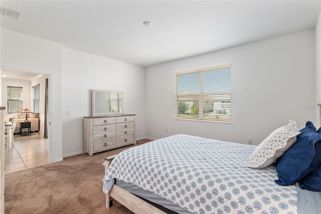 bedroom with tile patterned flooring, carpet, visible vents, and a textured ceiling