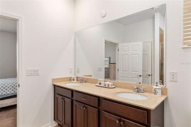 ensuite bathroom with double vanity, connected bathroom, and a sink