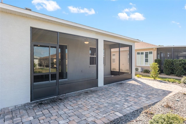 back of house featuring a sunroom, a patio area, and stucco siding