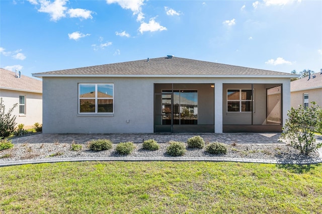 rear view of house with roof with shingles, a patio area, a lawn, and stucco siding