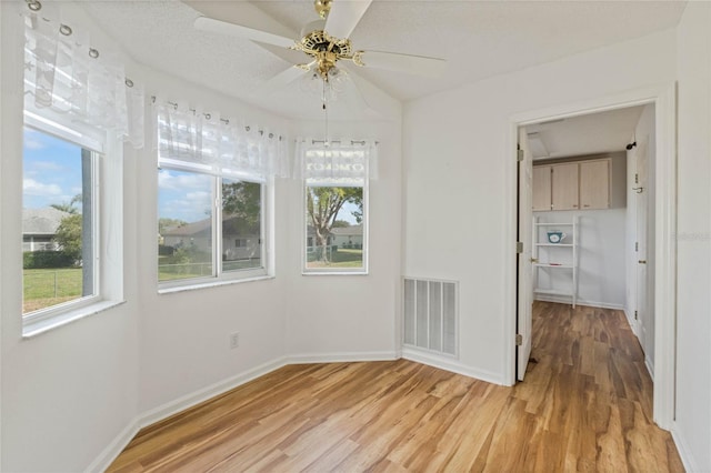 interior space with light wood-style floors, visible vents, baseboards, and a ceiling fan