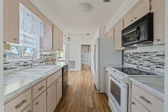 kitchen featuring electric stove, light countertops, light brown cabinets, a sink, and black microwave