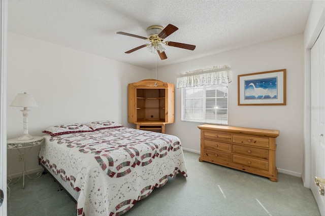 bedroom with light colored carpet, ceiling fan, a textured ceiling, and baseboards