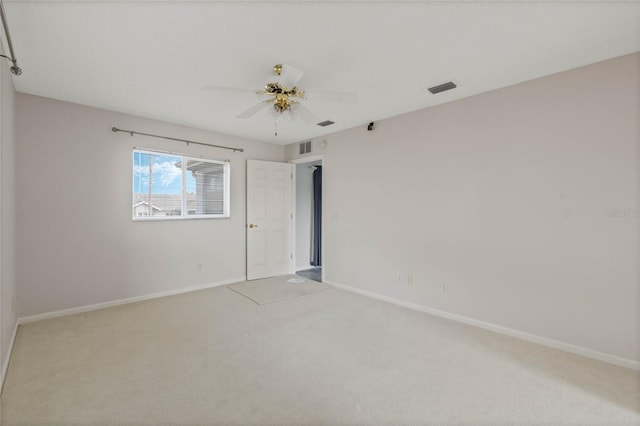 carpeted spare room featuring ceiling fan, visible vents, and baseboards