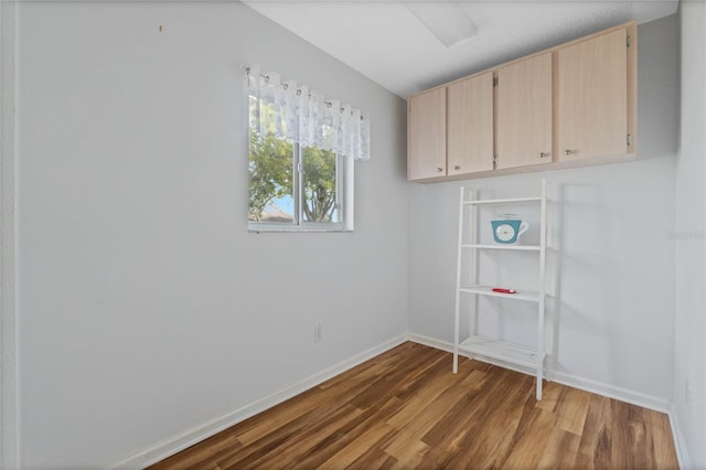 spare room with baseboards and wood finished floors