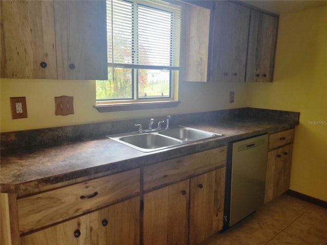 kitchen with dishwasher, dark countertops, a sink, and light tile patterned flooring