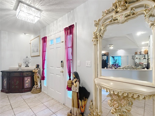 foyer entrance featuring light tile patterned flooring, ceiling fan, and a textured ceiling