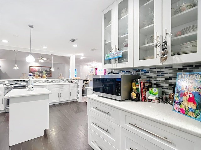 kitchen with stainless steel appliances, white cabinetry, visible vents, and decorative backsplash