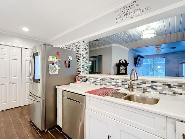 kitchen with decorative backsplash, appliances with stainless steel finishes, ornamental molding, wood finish floors, and a sink