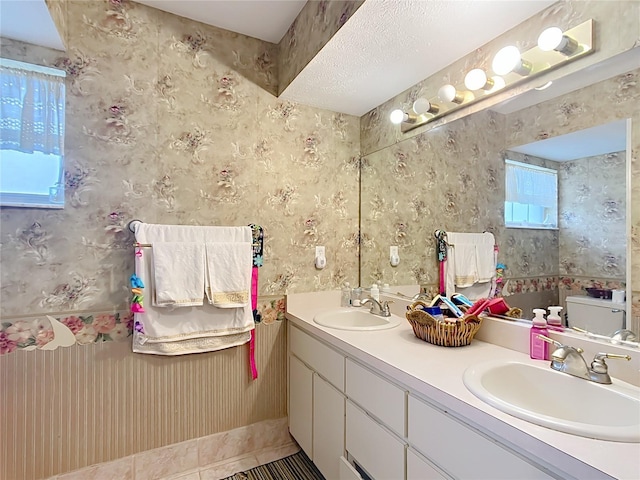 bathroom featuring double vanity, a sink, a tub, and wallpapered walls