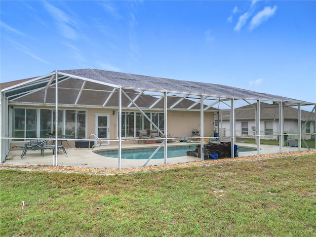 back of property with glass enclosure, an outdoor pool, a patio area, and a lawn