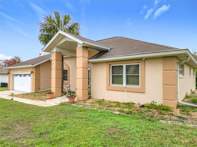 view of front of house with a garage, roof with shingles, a front yard, and stucco siding