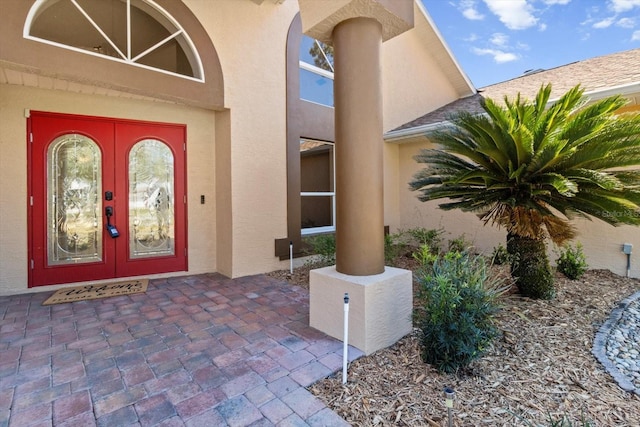 view of exterior entry featuring a shingled roof and stucco siding