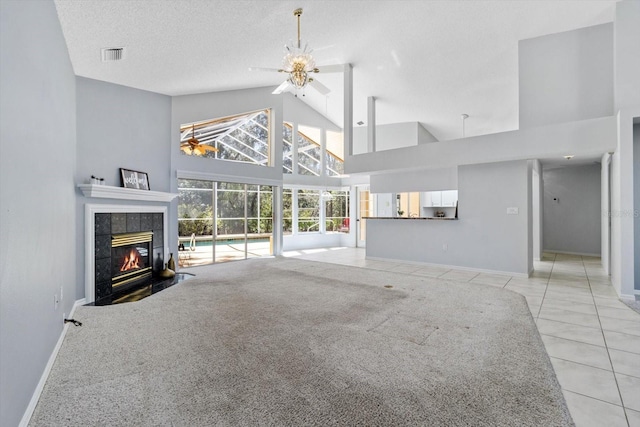 living room with light tile patterned floors, high vaulted ceiling, a textured ceiling, a fireplace, and visible vents