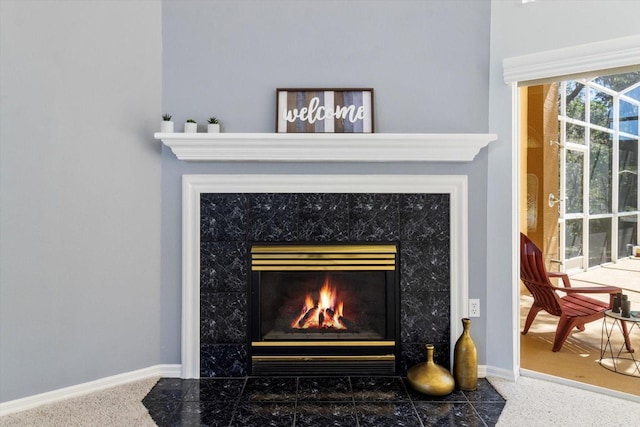 details with a tile fireplace, baseboards, and speckled floor