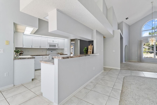 kitchen featuring high vaulted ceiling, white appliances, light tile patterned flooring, and white cabinetry