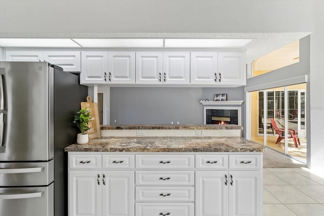 kitchen with freestanding refrigerator, white cabinetry, a peninsula, and a premium fireplace