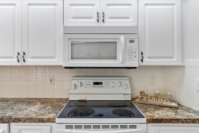 kitchen with dark countertops, white appliances, white cabinets, and decorative backsplash