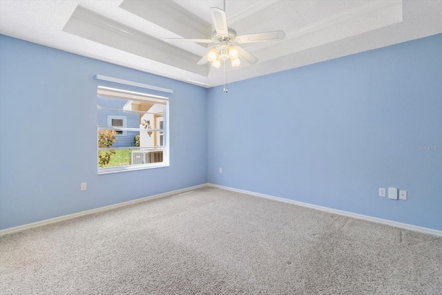 carpeted empty room with baseboards, a tray ceiling, and a ceiling fan