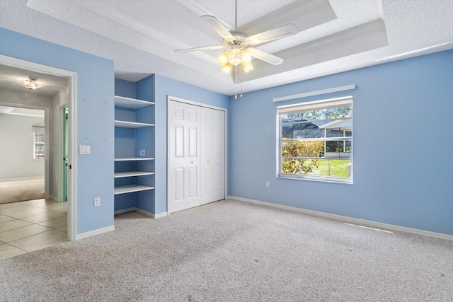 unfurnished bedroom with a textured ceiling, carpet floors, a closet, and a raised ceiling