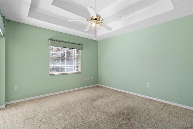 carpeted empty room featuring a textured ceiling, a raised ceiling, a ceiling fan, and baseboards