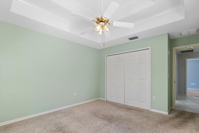 unfurnished bedroom featuring a tray ceiling, carpet flooring, and visible vents